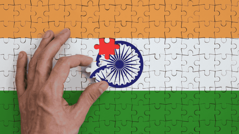Neue Chancen für Sourcing und Produktion Die Flagge Indiens ist auf einem Puzzle abgebildet, das die Hand des Mannes zum Zusammenklappen vervollständigt.